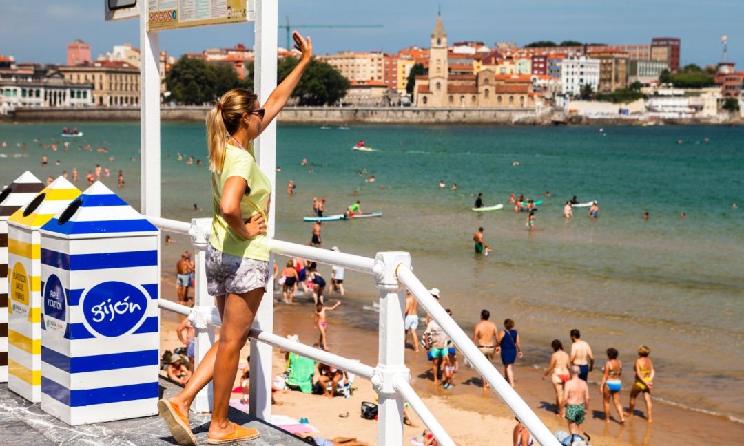 Una turista saluda desde una escalera de la playa de San Lorenzo. Una turista saluda desde una escalera de la playa de San Lorenzo.