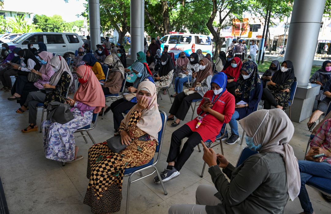 Varias personas esperan en un punto de vacunación en Indonesia. Varias personas esperan en un punto de vacunación en Indonesia.