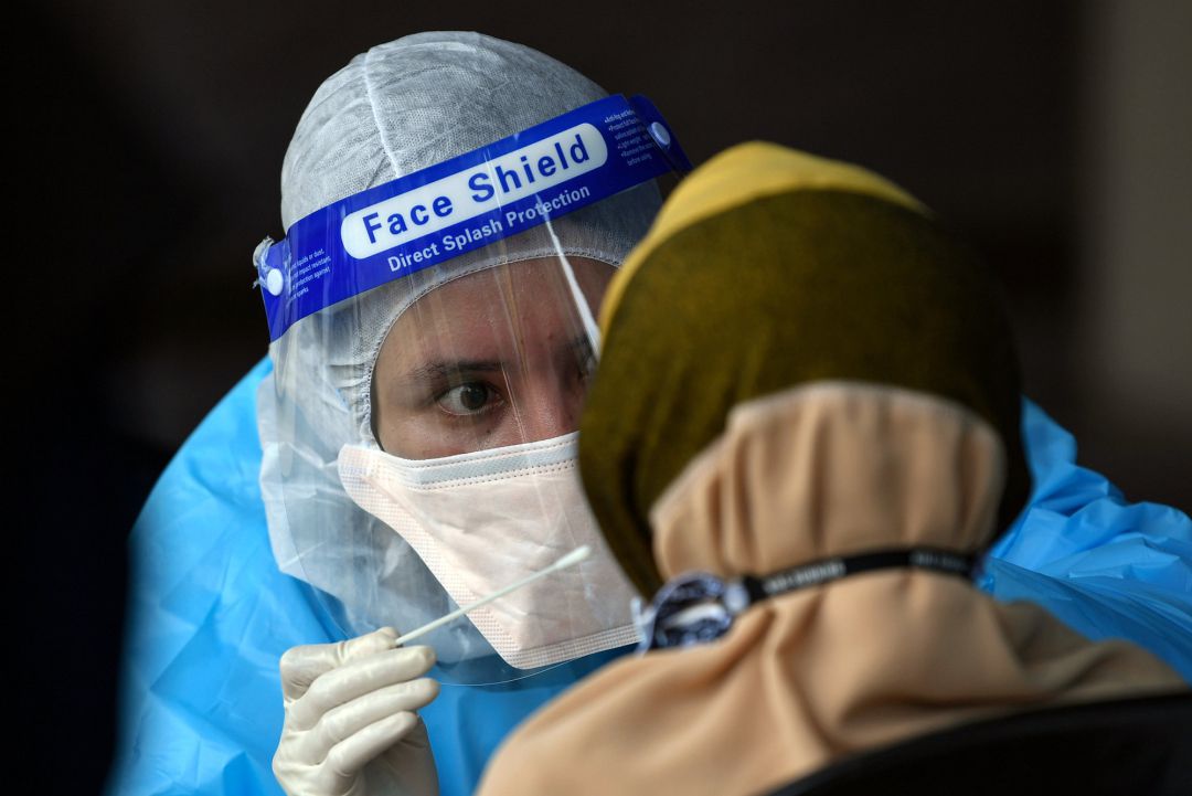 A health worker collects a swab sample from a woman for Coronavirus (Covid-19) PCR test A health worker collects a swab sample from a woman for Coronavirus (Covid-19) PCR test