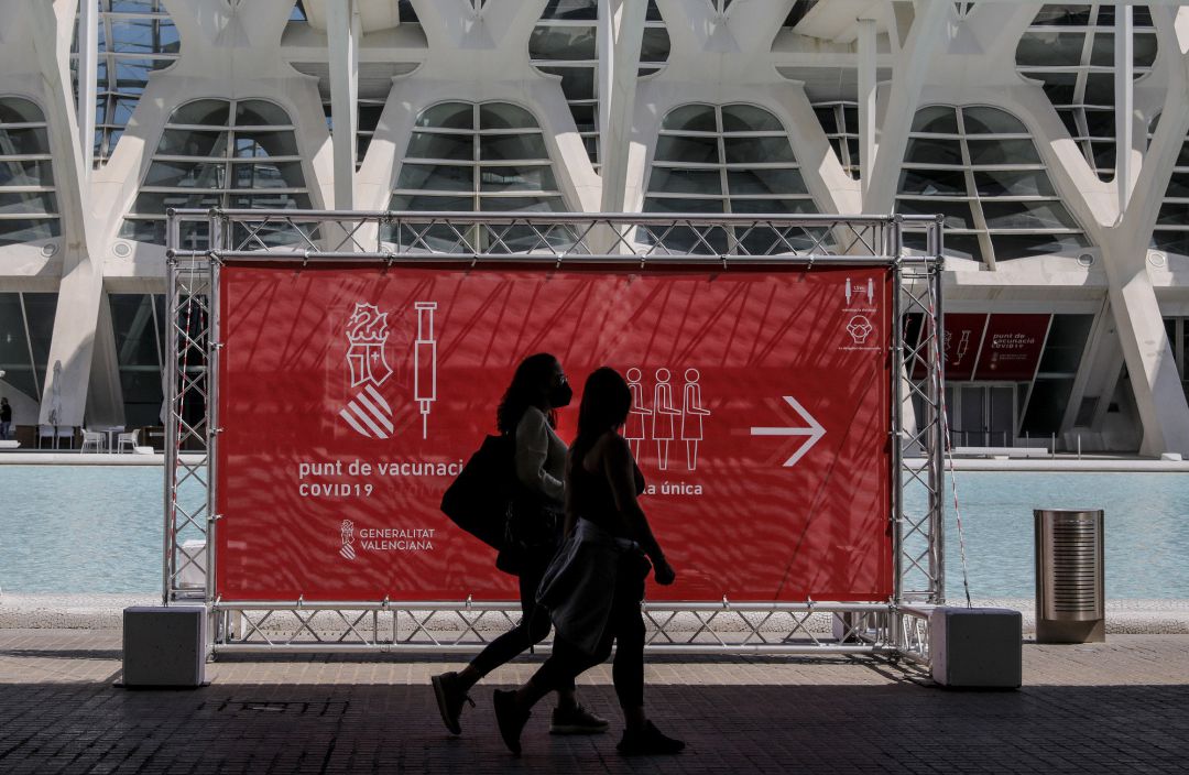 Dos personas pasan por un cartel que indica el punto de vacunación de la Ciudad de las Artes y las Ciencias de València Dos personas pasan por un cartel que indica el punto de vacunación de la Ciudad de las Artes y las Ciencias de València