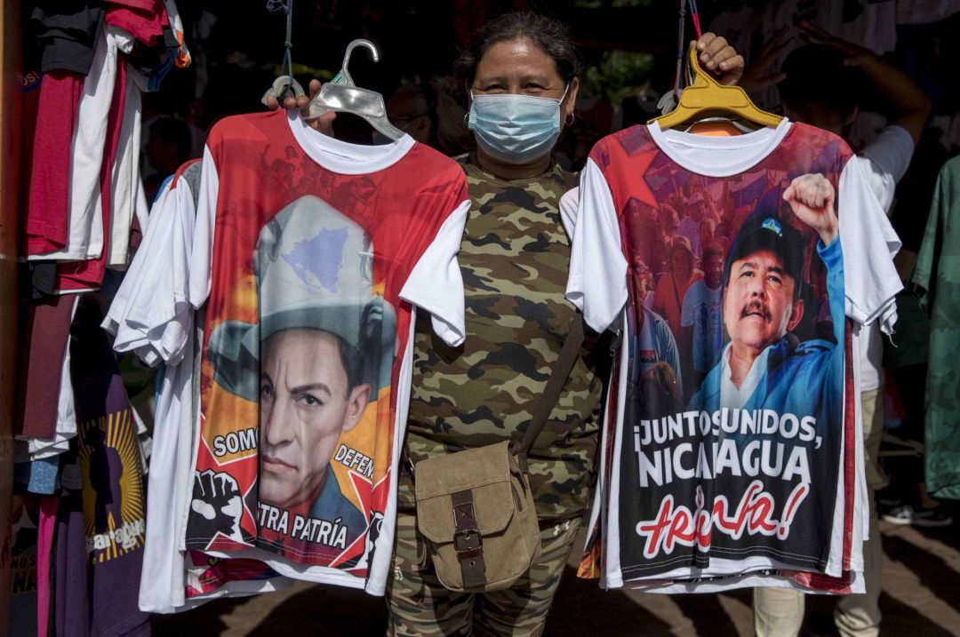 Una mujer posa para una fotografiá sosteniendo dos camisetas que muestran la imagen del héroe nacional Augusto C. Sandino (i) y el presidente de Nicaragua Daniel Ortega (d), en Managua (Nicaragua). El izquierdista Frente Sandinista de Liberación Nacional (FSLN) de Nicaragua ha celebrado su 60 aniversario con absoluto, aplastando a sus rivales internos, gobernando mediante la represión y el miedo, aislado y enfrentado con Occidente, y con el apoyo de Rusia, Cuba, Venezuela, Irán y Taiwán. Una mujer posa para una fotografiá sosteniendo dos camisetas que muestran la imagen del héroe nacional Augusto C. Sandino (i) y el presidente de Nicaragua Daniel Ortega (d), en Managua (Nicaragua). El izquierdista Frente Sandinista de Liberación Nacional (FSLN) de Nicaragua ha celebrado su 60 aniversario con absoluto, aplastando a sus rivales internos, gobernando mediante la represión y el miedo, aislado y enfrentado con Occidente, y con el apoyo de Rusia, Cuba, Venezuela, Irán y Taiwán.