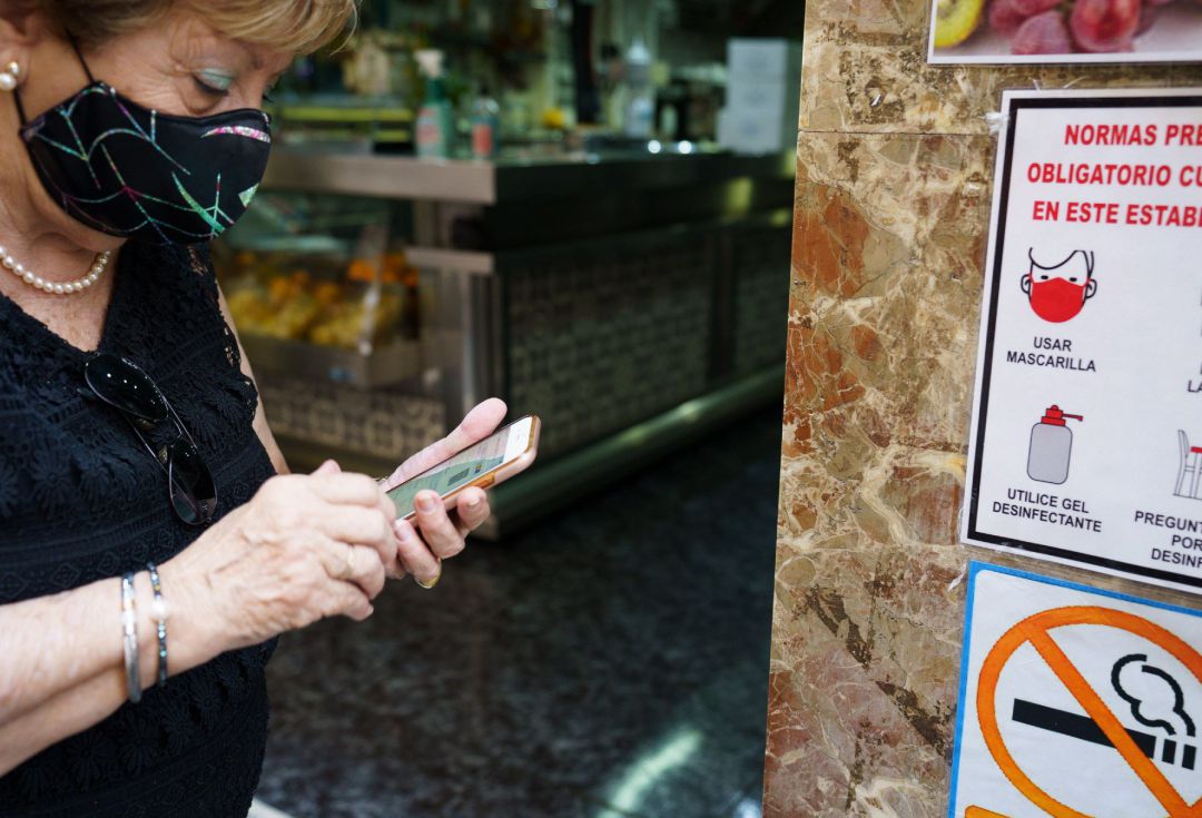 Una mujer busca en su móvil su certificado COVID momentos antes de acceder al interior de una cafetería de Santa Cruz de Tenerife. Una mujer busca en su móvil su certificado COVID momentos antes de acceder al interior de una cafetería de Santa Cruz de Tenerife.
