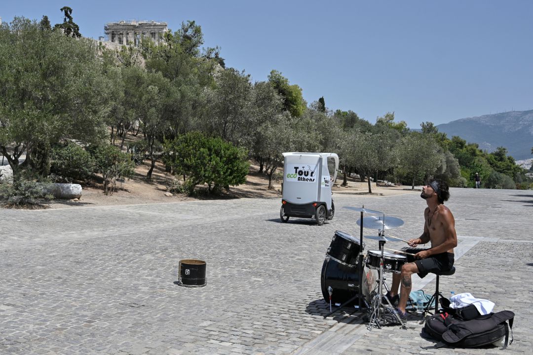Un músico callejero toca completamente solo en una zona turística de Atenas, este jueves, con temperaturas de hasta 44 grados. Un músico callejero toca completamente solo en una zona turística de Atenas, este jueves, con temperaturas de hasta 44 grados.