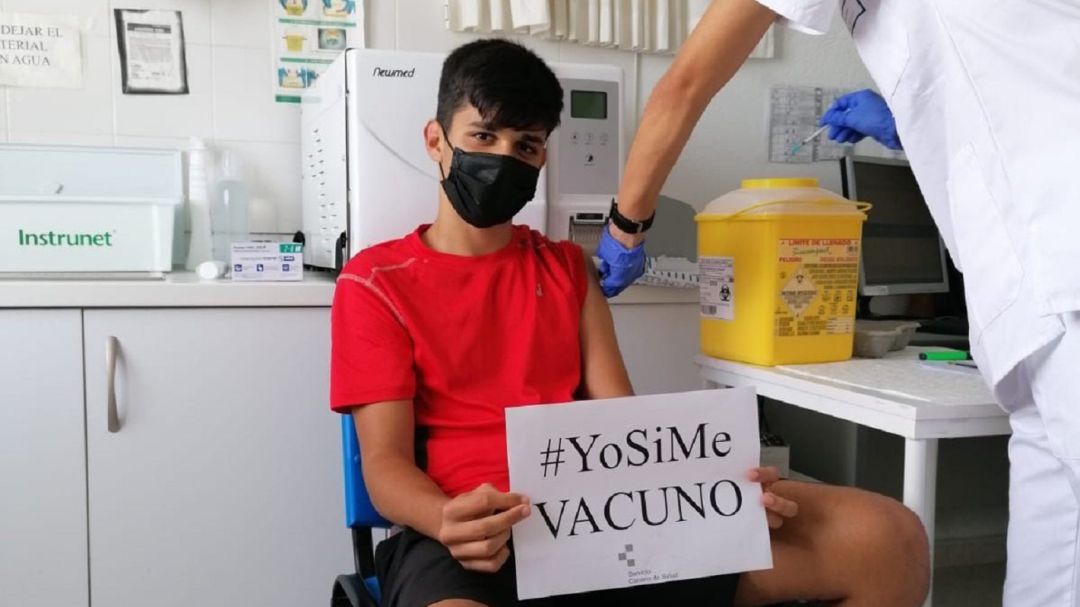 Un joven muestra un cartel para animar a vacunarse Un joven muestra un cartel para animar a vacunarse