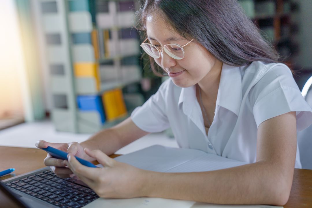 Una estudiante universitaria tailandesa, haciendo los deberes en una biblioteca pública. Una estudiante universitaria tailandesa, haciendo los deberes en una biblioteca pública.