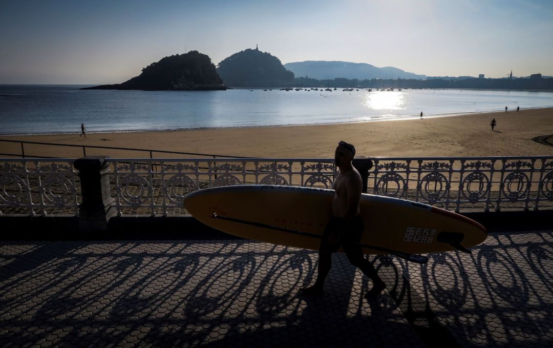 Un surfista pasea frente a la playa de Ondarreta, en una imagen de archivo Un surfista pasea frente a la playa de Ondarreta, en una imagen de archivo