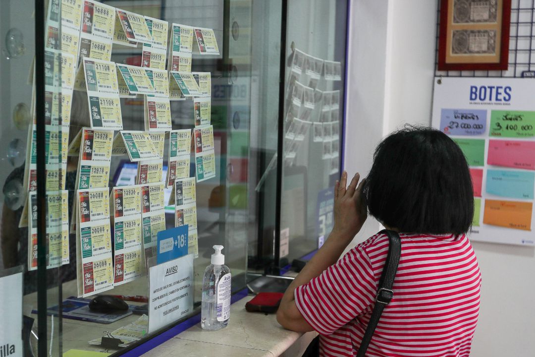Una mujer compra lotería en una administración Una mujer compra lotería en una administración