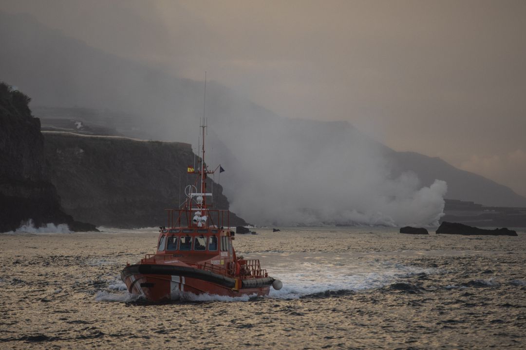 Un barco navega cerca de la columna de humo y la lava del volcán de Cumbre Vieja a su llegada al Océano Atlántico Un barco navega cerca de la columna de humo y la lava del volcán de Cumbre Vieja a su llegada al Océano Atlántico