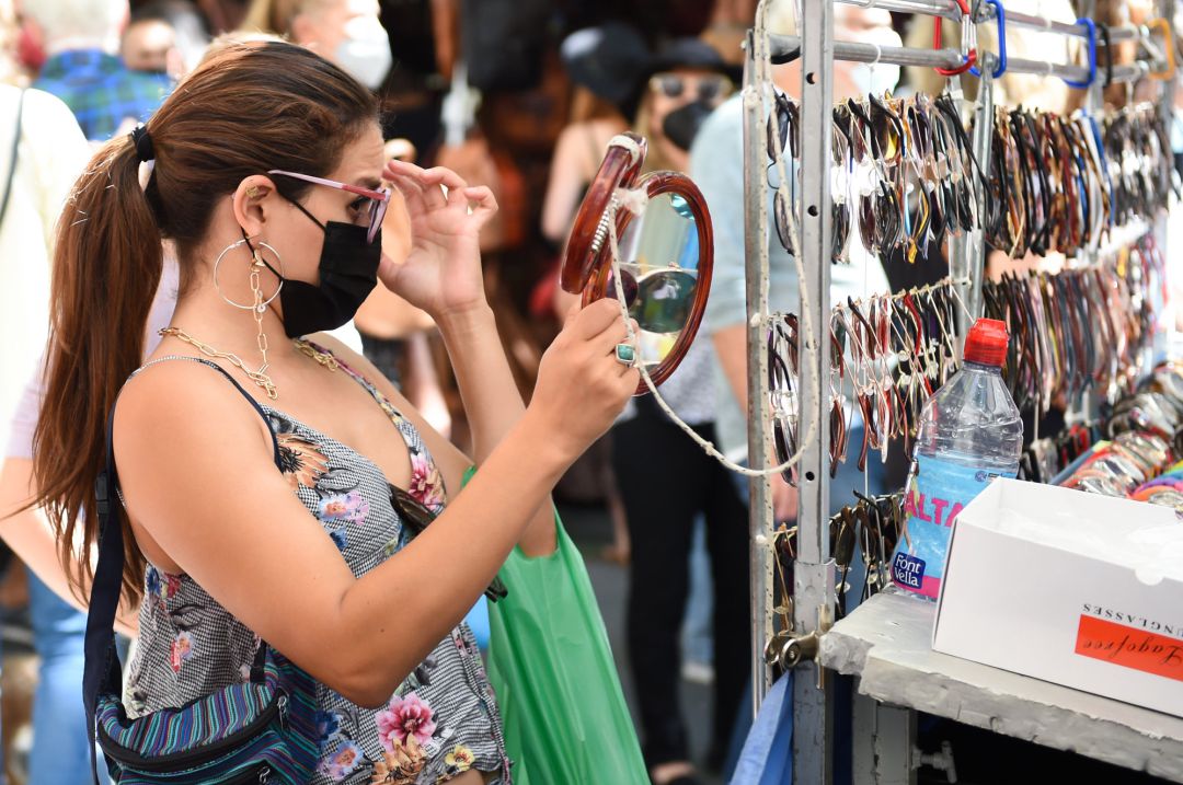 Una mujer con mascarilla se prueba unas gafas de sol que se venden en un puesto de El Rastro de Madrid. Una mujer con mascarilla se prueba unas gafas de sol que se venden en un puesto de El Rastro de Madrid.
