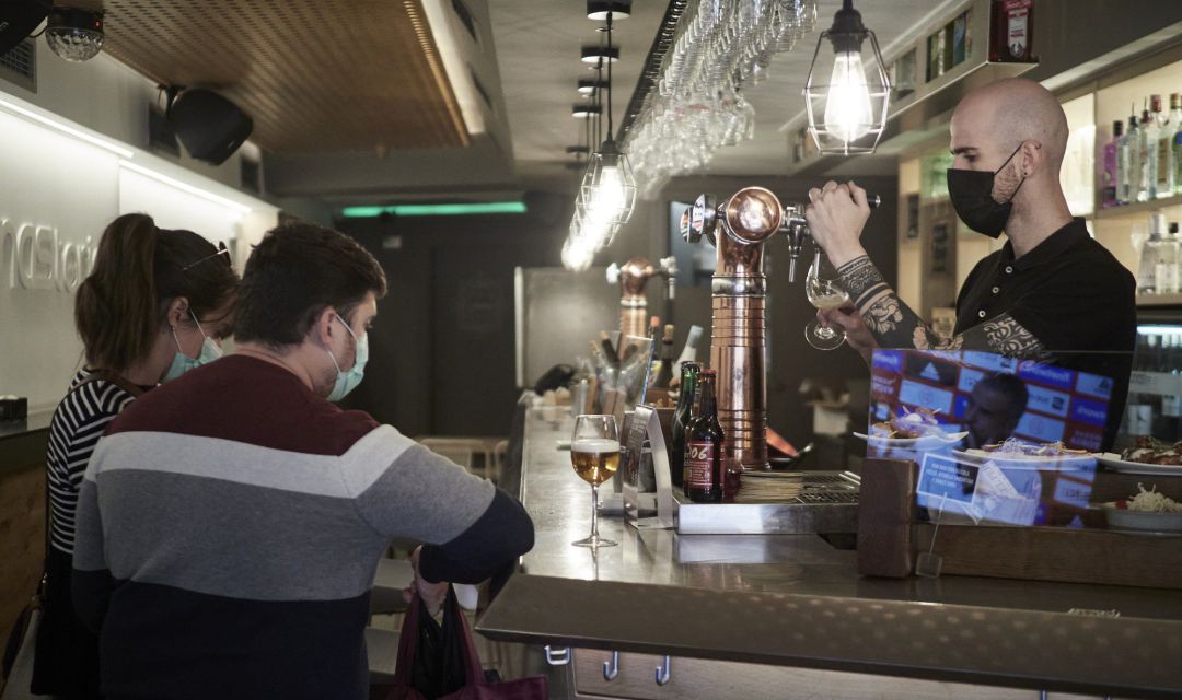 Un camarero sirve una cerveza en el interior de un bar. Un camarero sirve una cerveza en el interior de un bar.