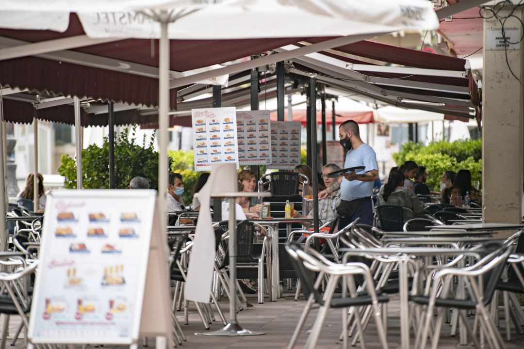 Un camarero atiende una mesa en la terraza de una cafetería Un camarero atiende una mesa en la terraza de una cafetería