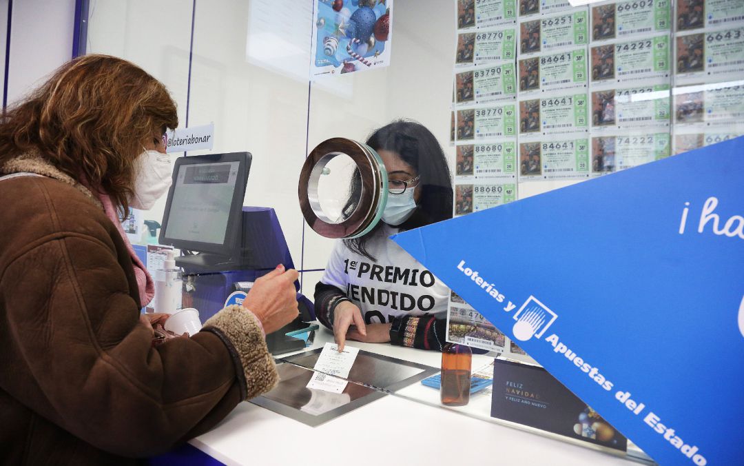 Archivo - Una lotera atiende a una clienta en la administración de lotería Archivo - Una lotera atiende a una clienta en la administración de lotería