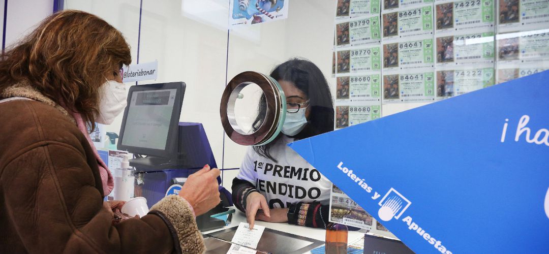 Una lotera atiende a una clienta en la administración de lotería Una lotera atiende a una clienta en la administración de lotería