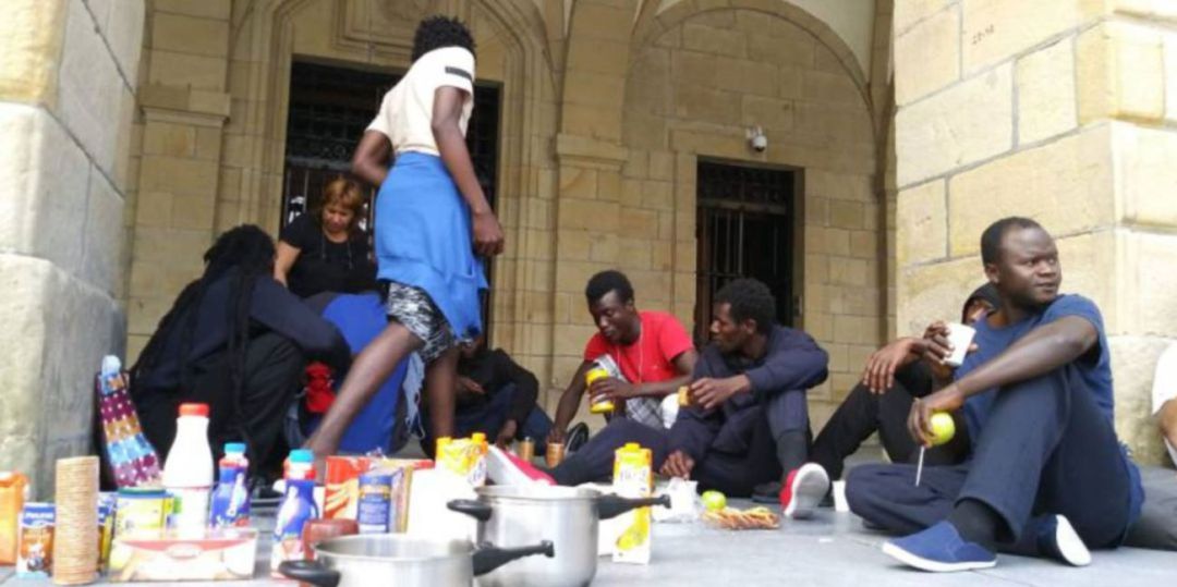 Persona migrantes recibiendo alimentos de la Red de Acogida Ciudadana en los arkupes del Ayuntamiento de Irun Persona migrantes recibiendo alimentos de la Red de Acogida Ciudadana en los arkupes del Ayuntamiento de Irun