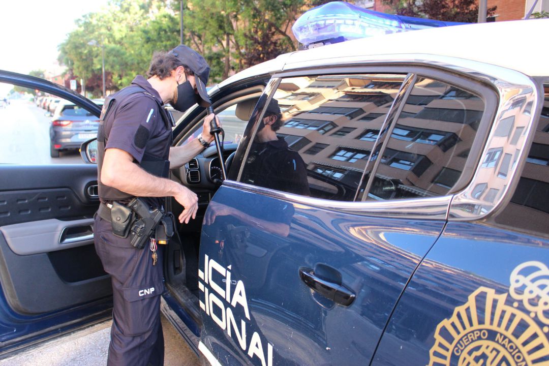 Un agente junto a un coche patrulla. Un agente junto a un coche patrulla.