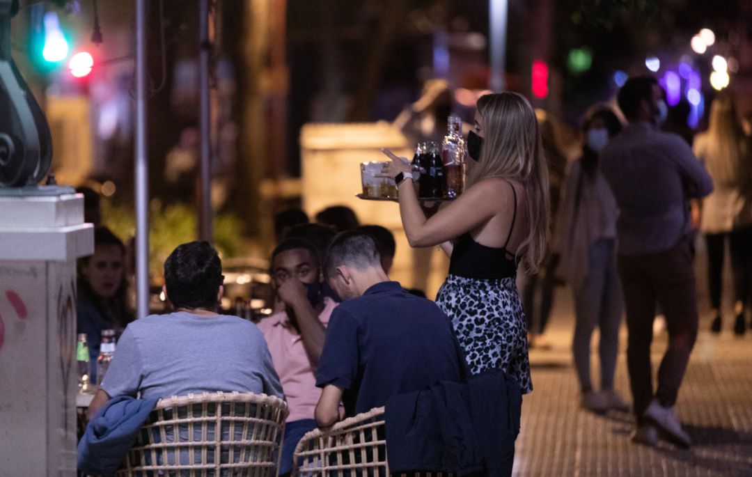 Una camarera atiende a varias personas en la terraza de un bar Una camarera atiende a varias personas en la terraza de un bar