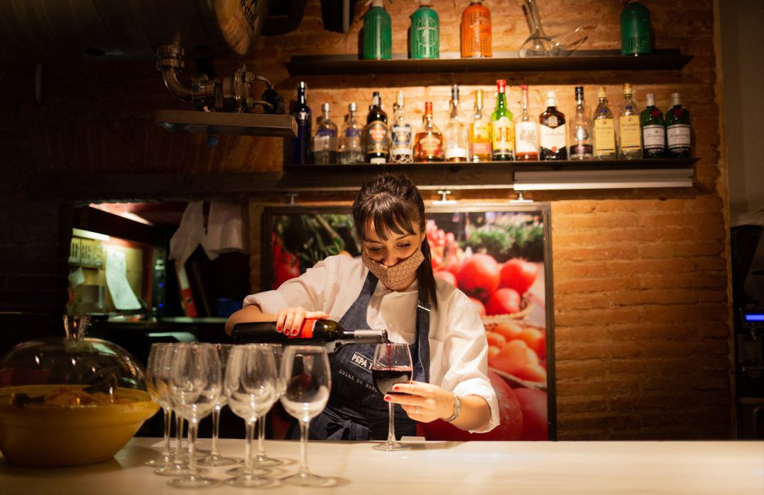 Una camarera sirve una copa de vino en el interior de un bar de Barcelona Una camarera sirve una copa de vino en el interior de un bar de Barcelona