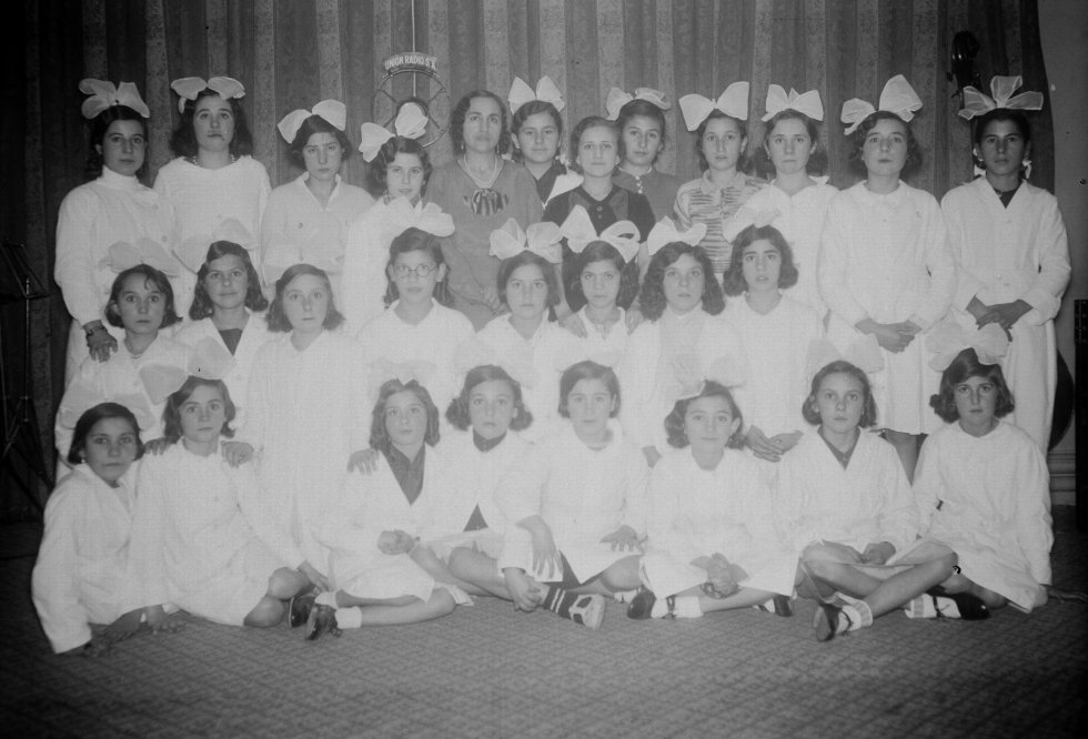 La Escuela Nacional de Chamartín de la Rosa visita las instalaciones de Unión Radio Madrid. Las niñas posan con sus profesoras, luciendo uniformes y unos gigantescos lazos en la cabeza. ¡Modas de los años 30! 