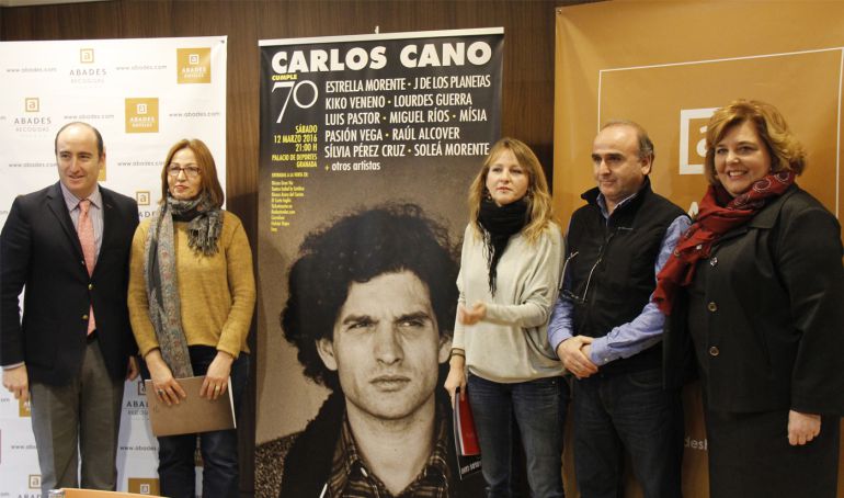 Presentación del concierto homenaje a Carlos Cano en Granada con su viuda y su hija a ambos lados del cartel anunciador, obra de Juan Vida