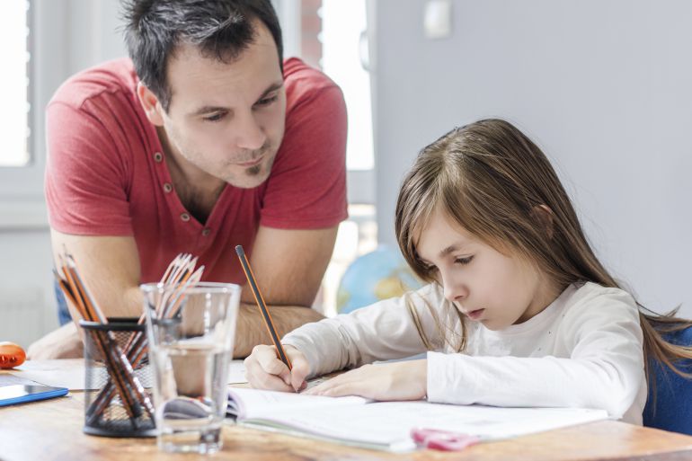 Un padre ayuda a su hija a hacer los deberes. 