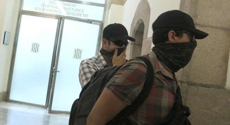 Dos agentes de la Guardia Civil con la cara tapada salen de las dependencias del Parlament catalán. 
