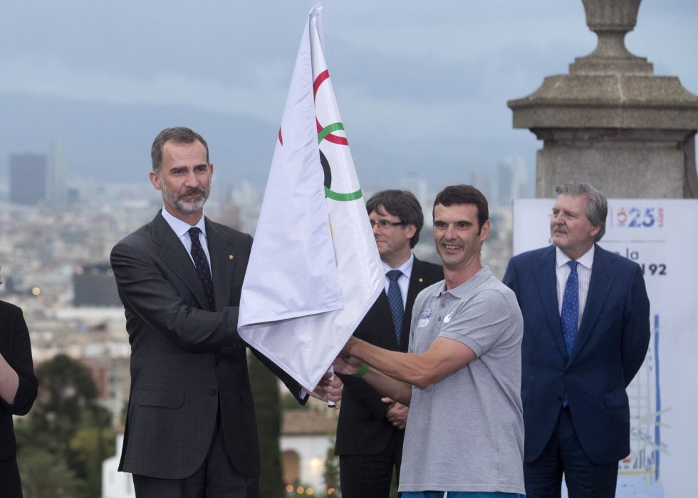 El rey Felipe VI entrega la bandera olímpica al primer portador, Carles Meilán, en presencia del ministro de Educación y Deportes, Iñigo Méndez de Vigo (1d) y el presiente de la Generalitat, Carles Puigdemont El rey Felipe VI entrega la bandera olímpica al primer portador, Carles Meilán, en presencia del ministro de Educación y Deportes, Iñigo Méndez de Vigo (1d) y el presiente de la Generalitat, Carles Puigdemont