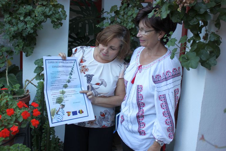 Mercedes Sánchez, concejala de inmigración y Lucica Loliceru miran el cartel anunciador de los cursos gratuitos de Rumano