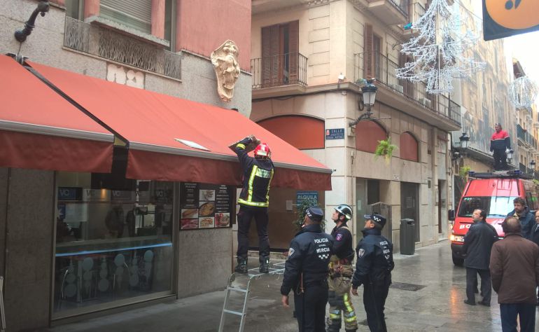 Un bombero de Murcia retira las dos losas de granito que han caído sobre el toldo de la cafetería