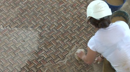 Una arqueologa limpia los restos de unos mosaicos del siglo I descubiertos en el transcurso de las obras de remodelacion de la villa romana de Bruñel