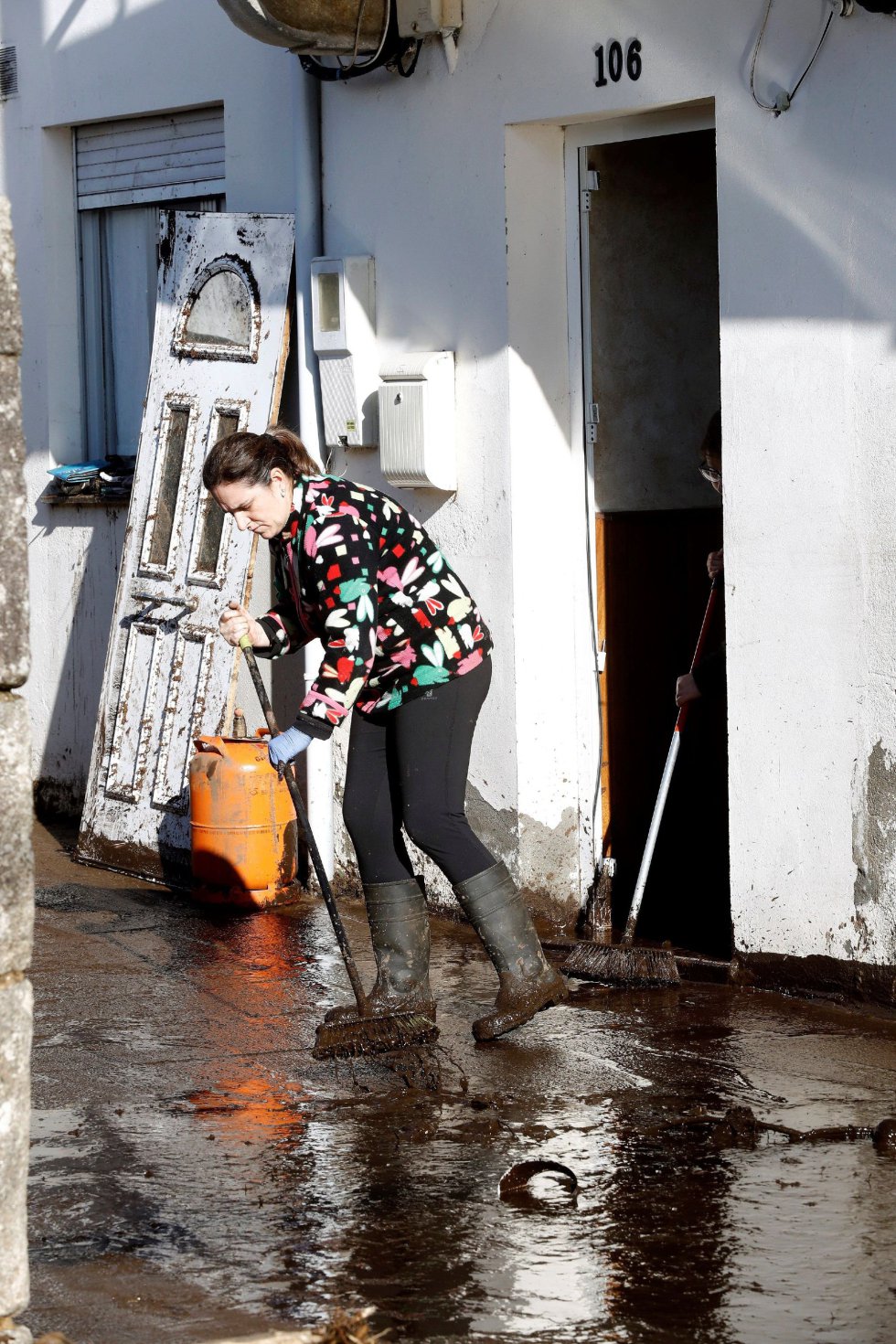 Una vecina limpia los restos de la riada junto a su vivienda en el barrio de Xunqueira. Una vecina limpia los restos de la riada junto a su vivienda en el barrio de Xunqueira.