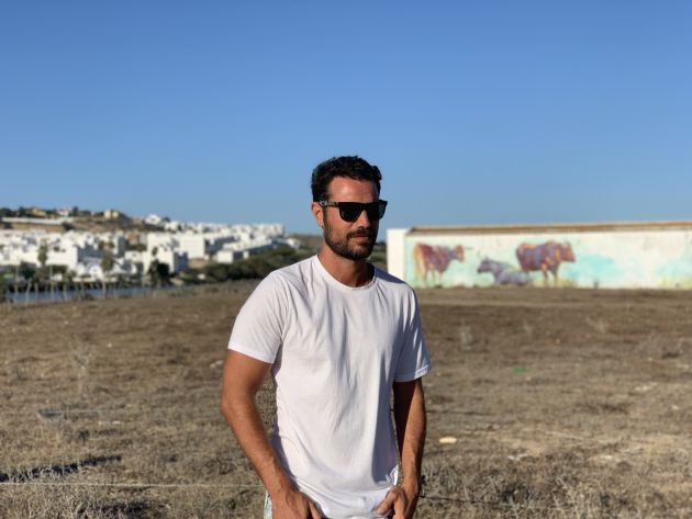 El pintor Adrián Torres posa ante uno de sus murales, en Conil (Cádiz)