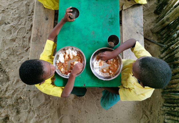 Un par de niños comen en el comedor de la escuela de Twashukuru