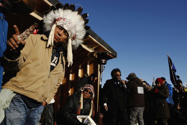 Oglala Sioux tribal elder Lance King (C) and Chief Arvol Looking Horse of Green Grass South Dakota, who is the spiritual leader of the Lakota, Dakota and Nakota Sioux Nations (C) listen as activist Dr. Cornel West speaks during an interfaith ceremony inside of the Oceti Sakowin camp as demonstrations continue against plans to pass the Dakota Access pipeline near the Standing Rock Indian Reservation, near Cannon Ball, North Dakota, U.S., December 4, 2016.  