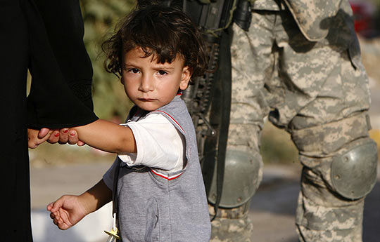 Un niño camina junto a su madre y un soldado en Bagdag.