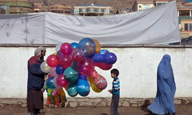 Un niño compla globos a un vendedor callejero