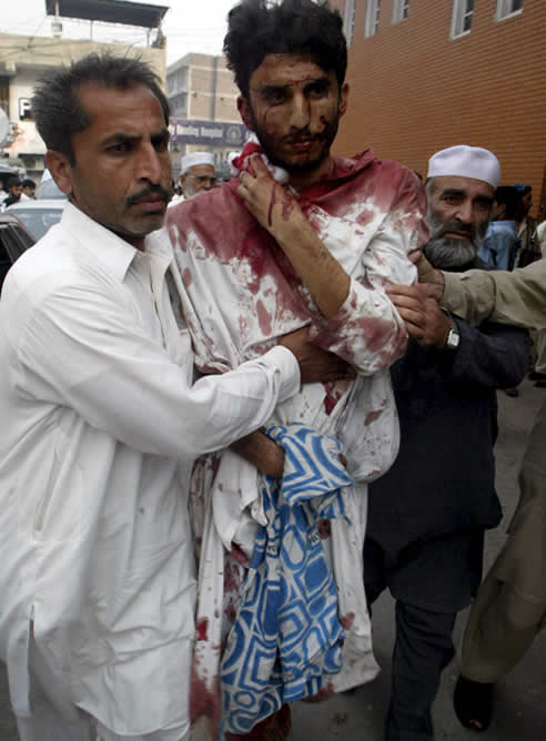 Varias personas trasladan a una de las víctimas de un ataque suicida perpetrado en una mezquita en Pakistán. (EFE / Arshad Arbab)