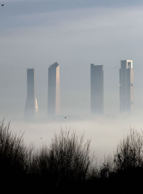 La niebla que cubre esta mañana parte de Madrid, y que ha obligado a cancelar vuelos en Barajas, se recorta contra las cuatro torres del paseo de la Castellana, desde Aravaca, a la salida de la ciudad por la A-6