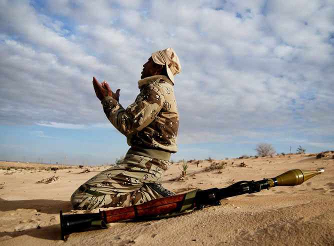 Un rebelde libio reza ayer lunes antes de iniciar el ataque sobre el Ejército de Muamar al Gadafi en el desierto, cerca de Ajdabiya, en la zona oriental del país, un bastión de los insurgentes asediado por las tropas gubernamentales.