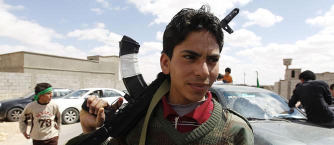 Un joven fiel Muamar el Gadafi sostiene un rifle en la base de Bani Walid