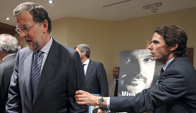 El expresidente Aznar coge del brazo a Rajoy durante la presentación de un libro