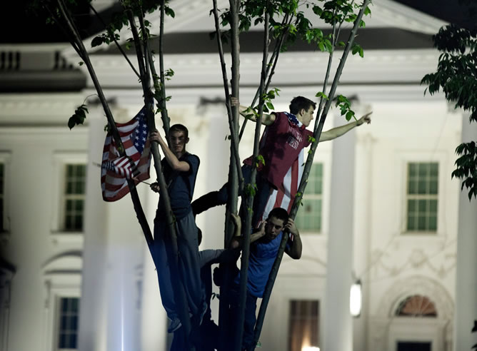 Unos jóvenes que permanecen en un árbol sobre la avenida Pennsylvania a las afueras de la Casa Blanca reaccionan hoy, lunes 2 de mayo de 2011, tras el anuncio hecho por el presidente de EEUU, Barack Obama, en una alocución sobre la muerte del terrorista más buscado del mundo, Osama bin Laden