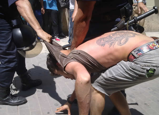 Uno de los 'indignados' que este jueves se han concentrado frente a las Cortes Valencianas en el momento en el que un agente le detiene