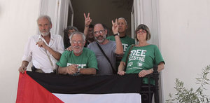 Activistas españoles de la plataforma 'Rumbo a Gaza' miran a la cámara desde el balcón de la embajada