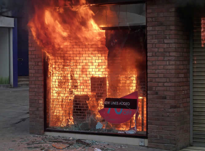 Un almacén de ropa arde durante la cuarta noche de disturbios