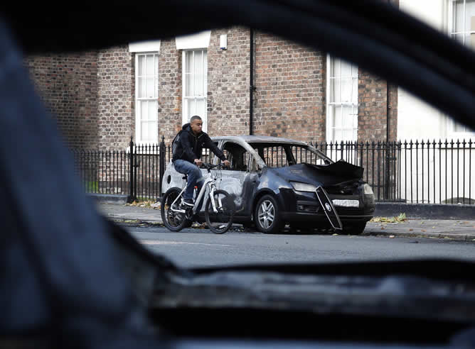 Un hombre pasa en bicicleta por la zona afectada por los disturbios esta madrugada en Liverpool