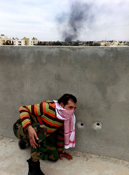 Un rebelde, a cubierto, durante el tiroteo que se ha producido  en Misrata.