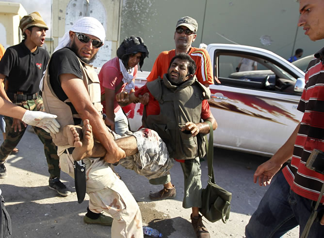 Rebeldes libios cargan con un compañero herido por fuego enemigo.