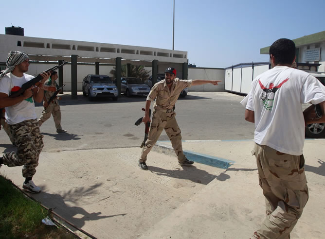 Soldados rebeldes toman posiciones en el asalto a un centro militar de formación de mujeres donde se encontraban varios soldados afines a Gadafi.