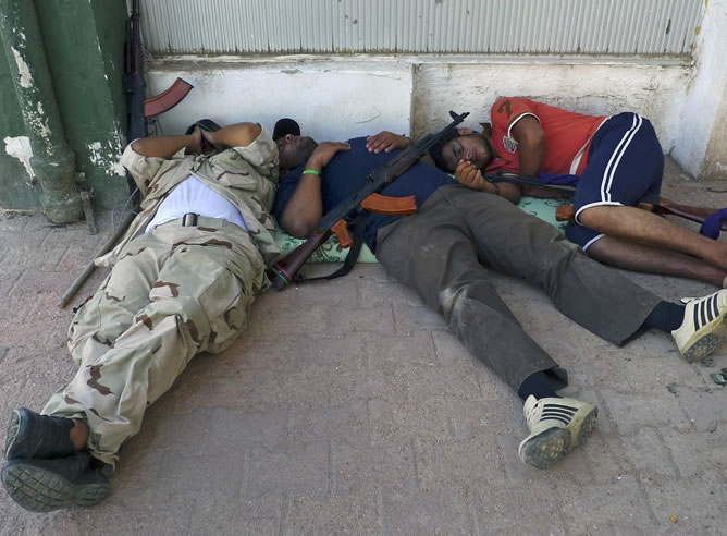Rebeldes libios descansan tras el ataque contra los afines al régimen de Gadafi. El ataque se ha producido en un centro de formación militar para mujeres.
