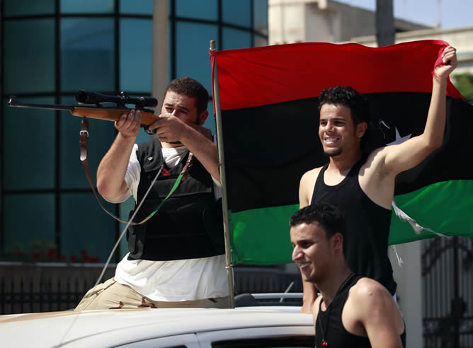 Varios rebeldes celebran, con la bandera tricolor del Consejo Nacional de Transición, su avance en Trípoli